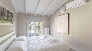 Una camera da letto con un letto, un condizionatore d'aria bianco, un quadro incorniciato e vista attraverso una porta in vetro.