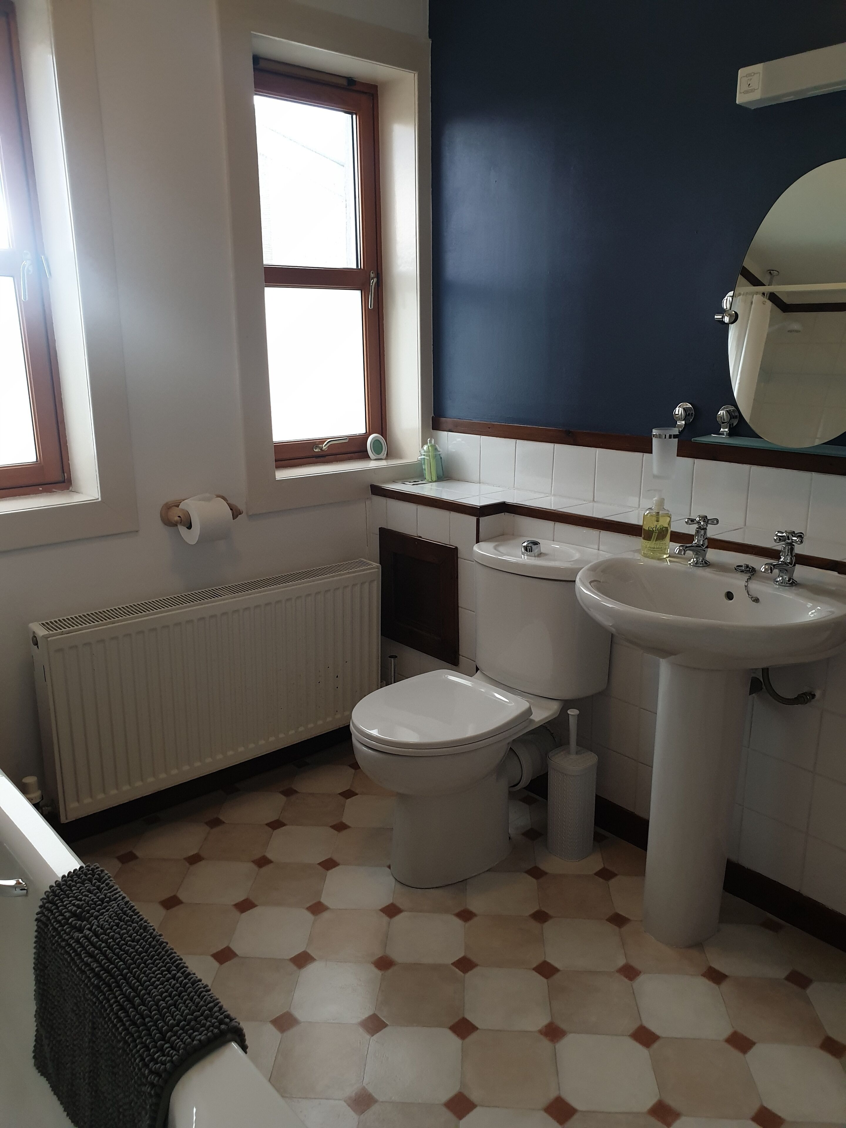 A bathroom with a toilet, sink, and window.