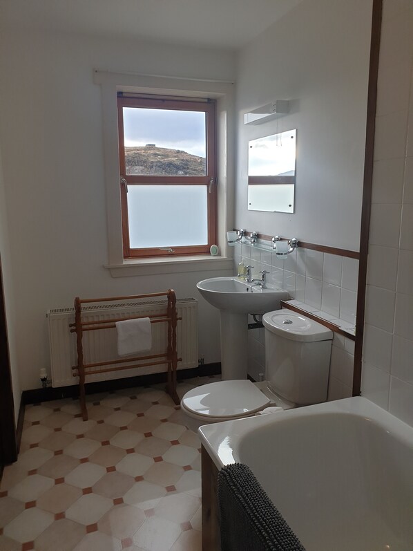 A bathroom with a window, a radiator, a sink, a toilet, and a bathtub. - Loch Erisort House (Isle of Lewis)