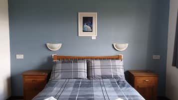 A neatly made bed with a checkered bedspread, two bedside tables, and a framed picture on the wall.