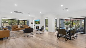 Ein geräumiges Wohnzimmer mit einer Couch, Sesseln, einem Kamin und einem Essbereich mit Tisch und Stühlen.