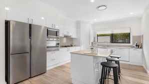 Eine moderne Küche mit Edelstahl-Kühlschrank, Einbauofen, Mikrowelle und einer großen Kücheninsel mit Barhocker.