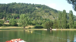 A lake with boats docked, surrounded by forested hills and houses.