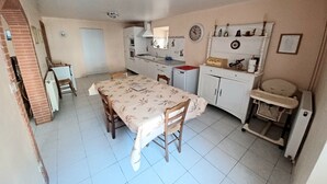 A compact kitchen with a dining table, chairs, a refrigerator, a sink, and a small cabinet.