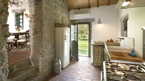 A rustic kitchen with stone walls, a wooden ceiling, and a gas stove. - 3 Bedroom Private vacation home in Arzachena (Arzachena)