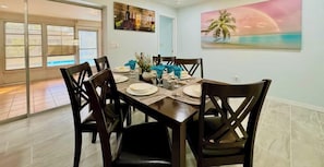 A dining area with a rectangular table, dark wooden chairs, and a view of the outside. - Coastal Charm with Heated Pool (Cape Coral)