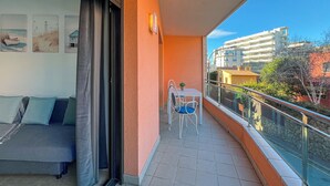 A balcony with a table and chairs, a sofa, and a sliding glass door leading to a living area. - Apartment for 3 people, free Wi-Fi in the center of Lloret, 300 meters from the beach, ideal for young people. (Lloret de Mar)