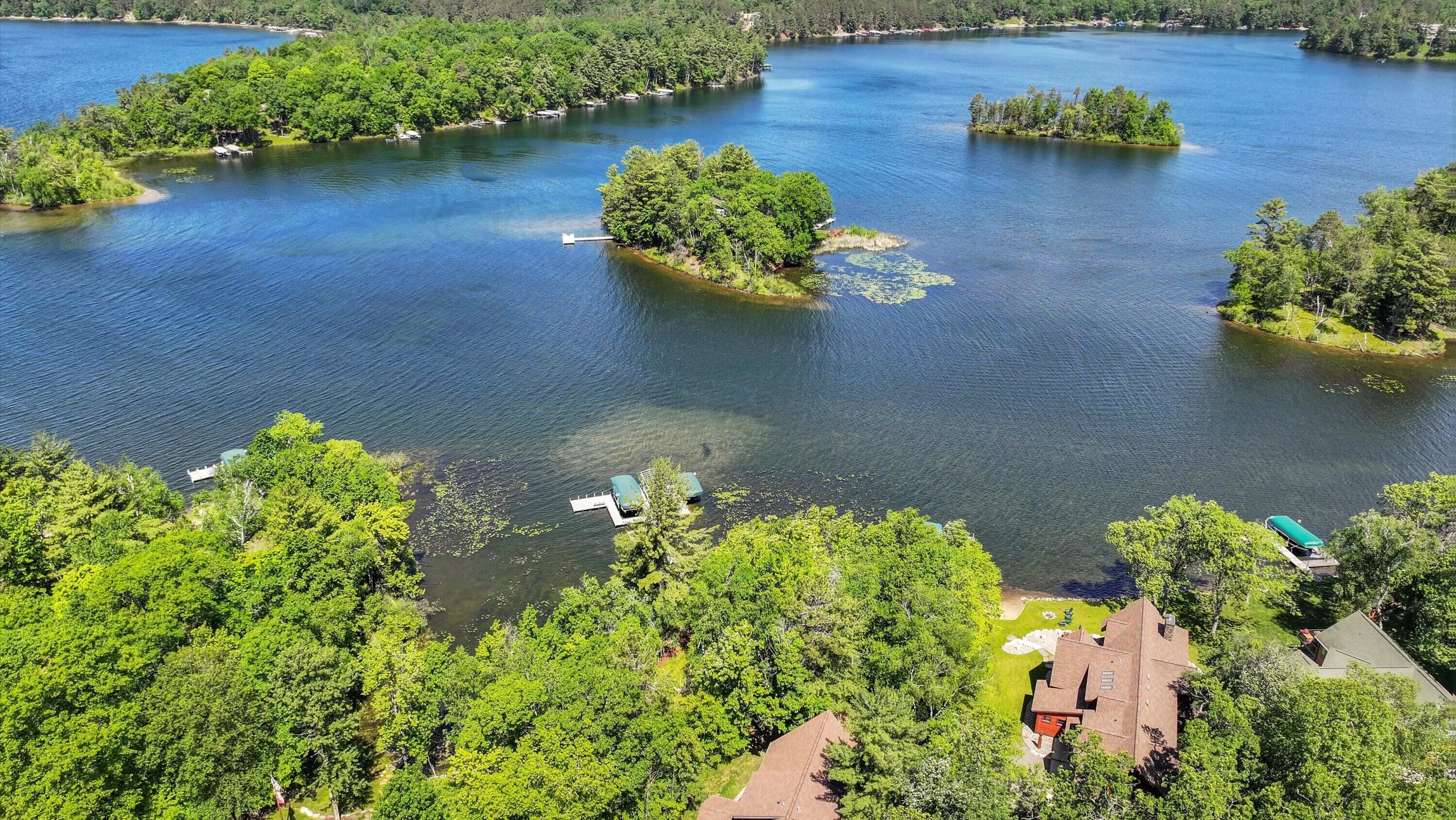 A lakeside property with multiple islands, clear water, and lush greenery.