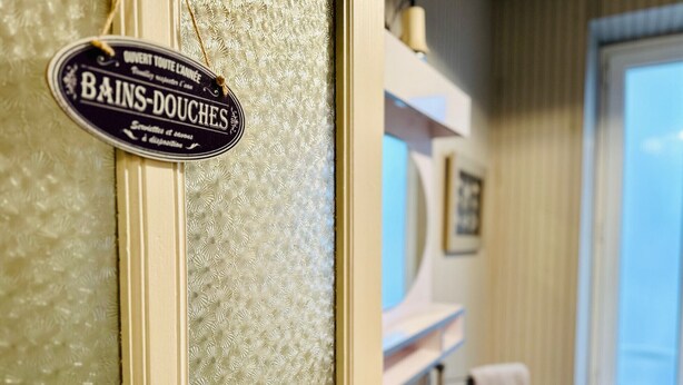 Un baño con un letrero que dice "BAINS-DOUCHES" y un papel tapiz estampado.