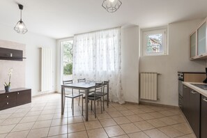 A modern kitchen with a dining table, chairs, a built-in oven, and a window with a view of greenery. - 1 Bedroom Apartment in Desenzano del Garda (Desenzano del Garda)