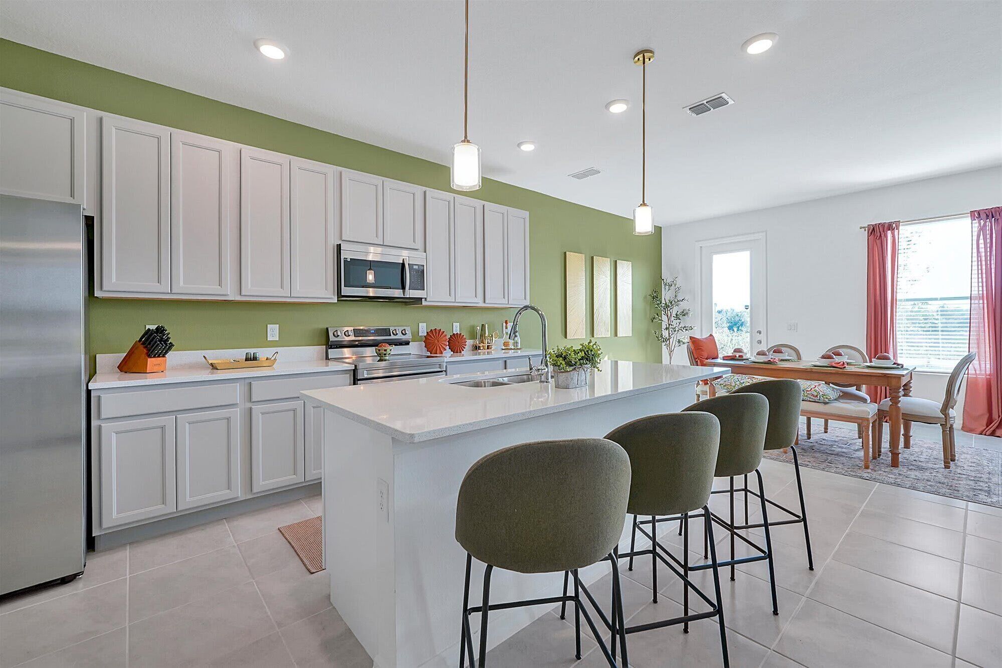 A modern kitchen with white cabinets, a central island, and bar stools.
