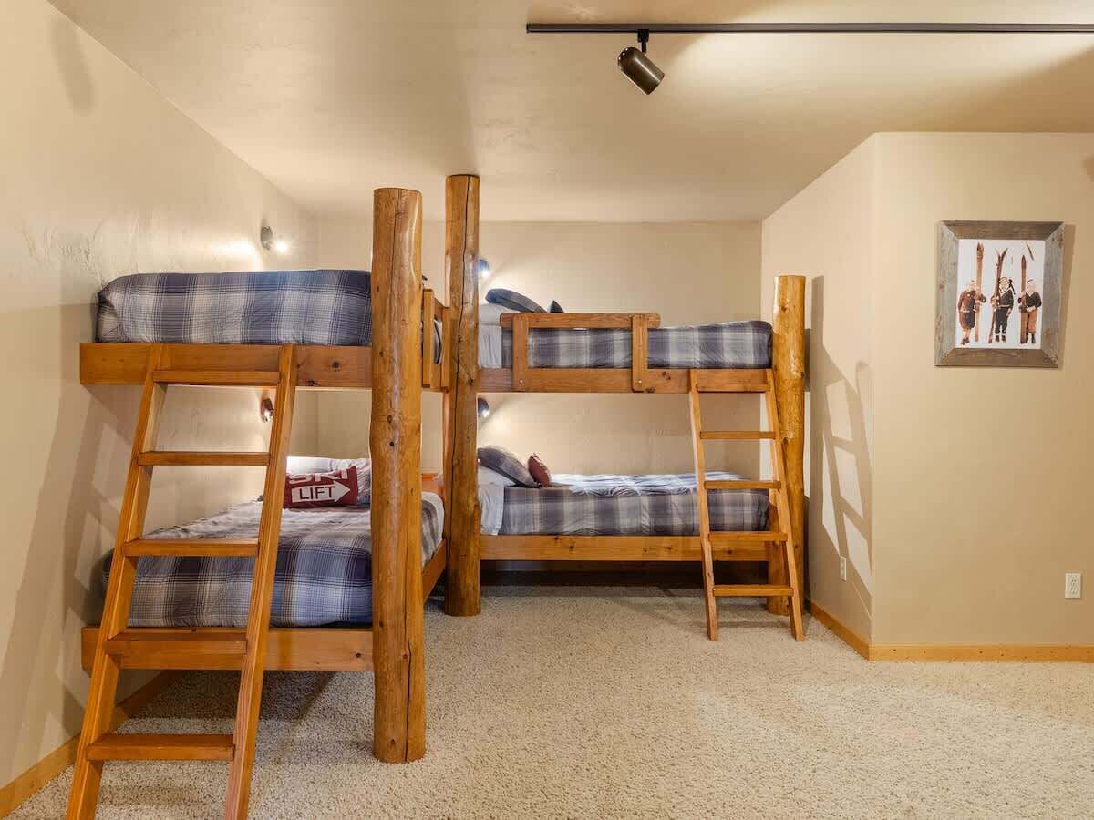 A bunk bed room with a ladder, a framed picture on the wall, and a carpeted floor.
