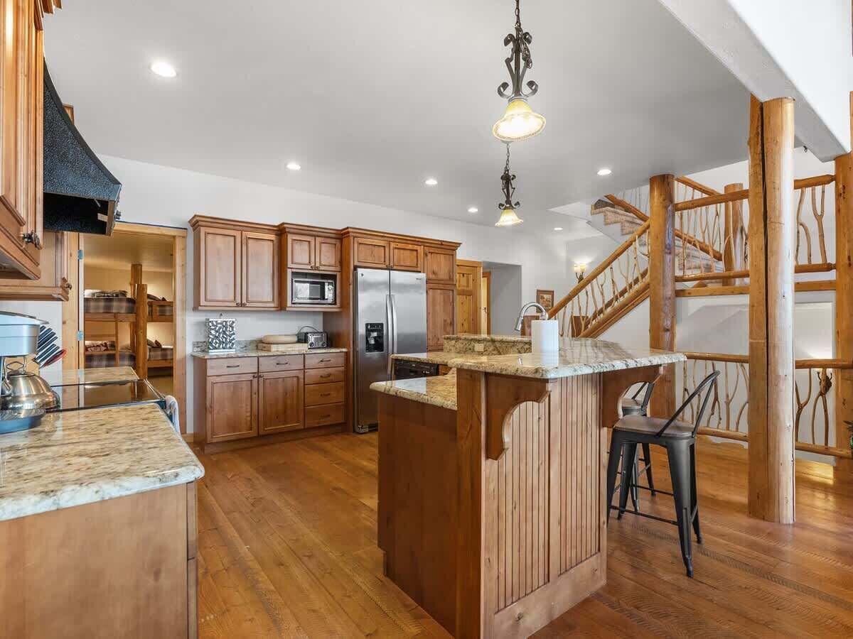 A kitchen with wooden cabinets, a central island, stainless steel appliances, and a staircase.