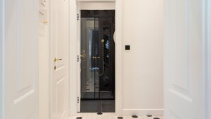 A hallway leading to a room with a glass door, white walls, and a tiled floor. - Candy Cavalier Zagreb Center Lux (Zagreb)