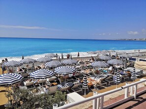 A beachside hotel with rows of striped umbrellas and lounge chairs facing the ocean.