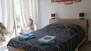 A bedroom with a bed, two bedside tables, a ceiling fan, and a window with curtains.