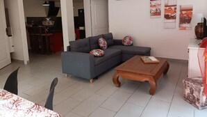 A modern living room with a grey sectional sofa, a wooden coffee table, and a dining area with a table set for two.