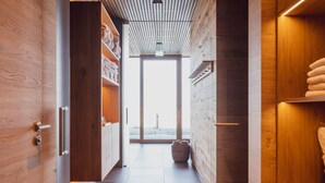 A hallway with wooden walls and a tiled floor, leading to a large glass door that opens to a balcony. - Hotel Munde (Hofstetten)