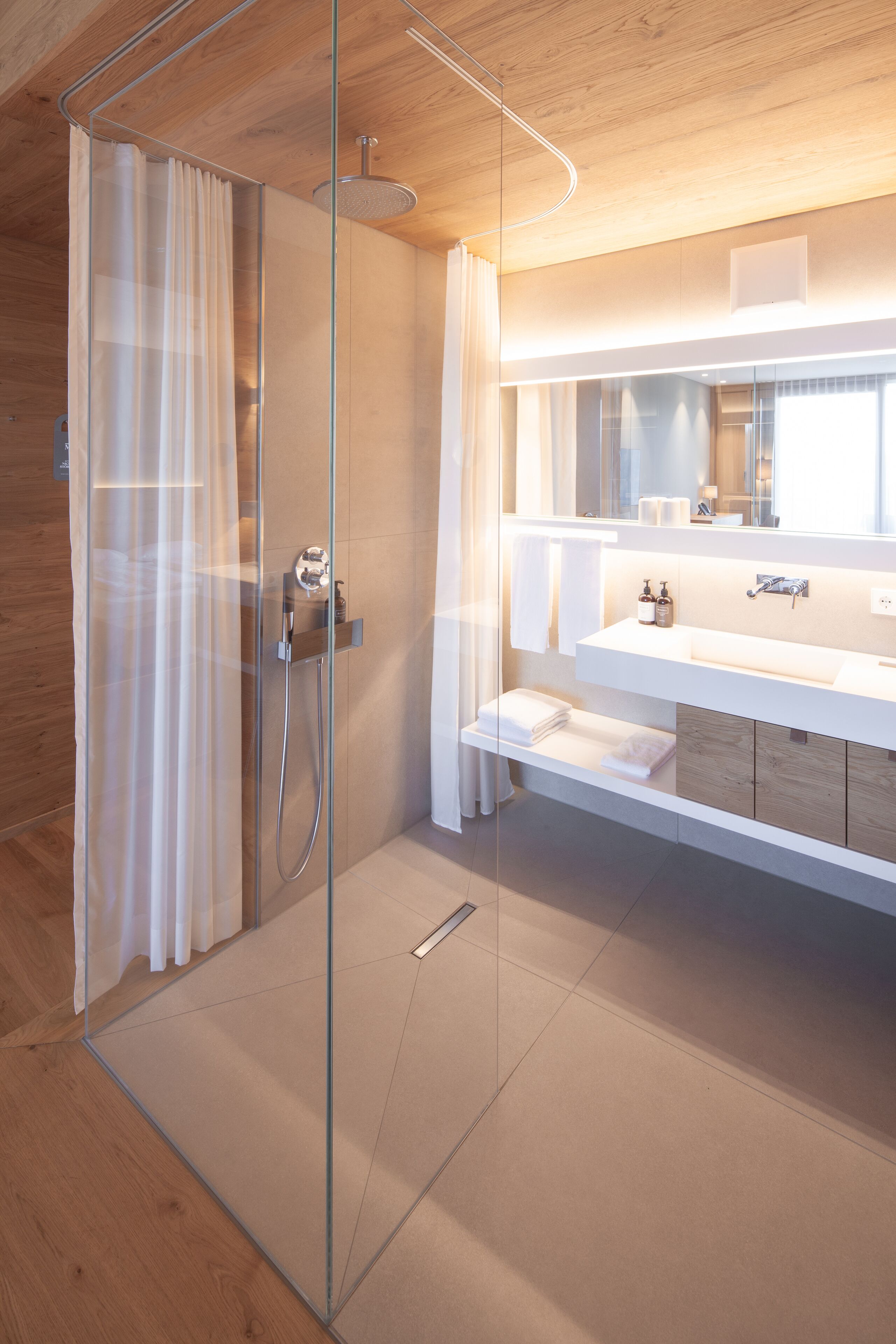 A modern bathroom with a glass shower enclosure, a white vanity with a mirror, and a wooden ceiling.