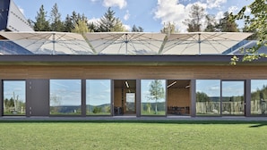 A modern building with large glass windows, a covered outdoor area, and a view of the surrounding landscape. - Hotel Munde (Hofstetten)