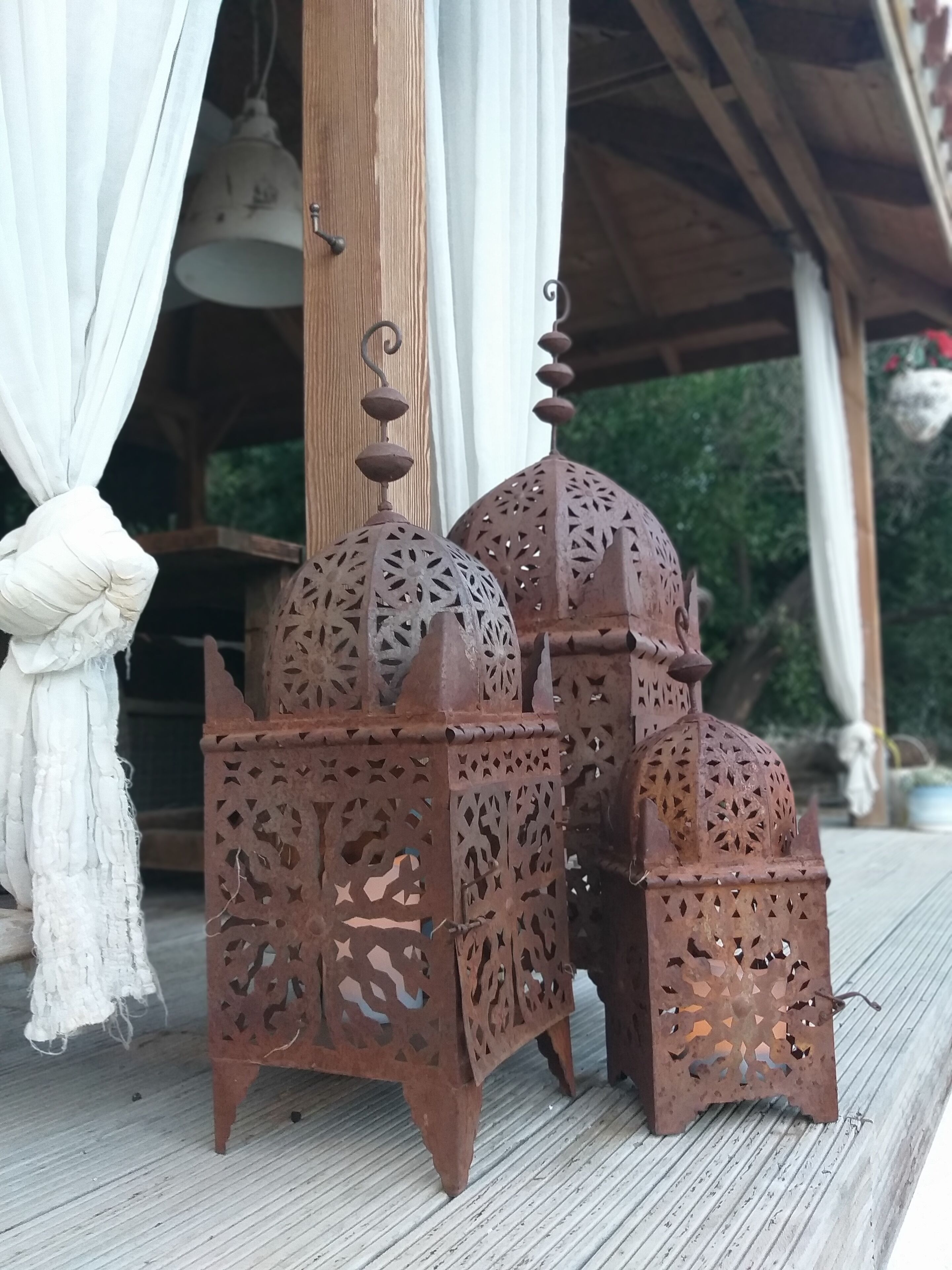A wooden structure with ornate metal lanterns and a hanging bell.