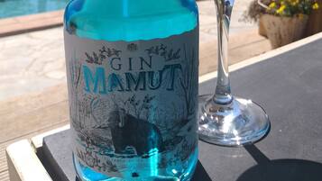 A bottle of gin and a glass of cocktail on a table by a pool.