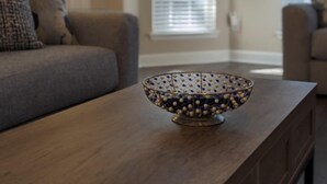 A modern living room with a wooden coffee table, a patterned bowl, and a lamp. - Cedar's Corner in Concord | Spacious & Clean (Concord)