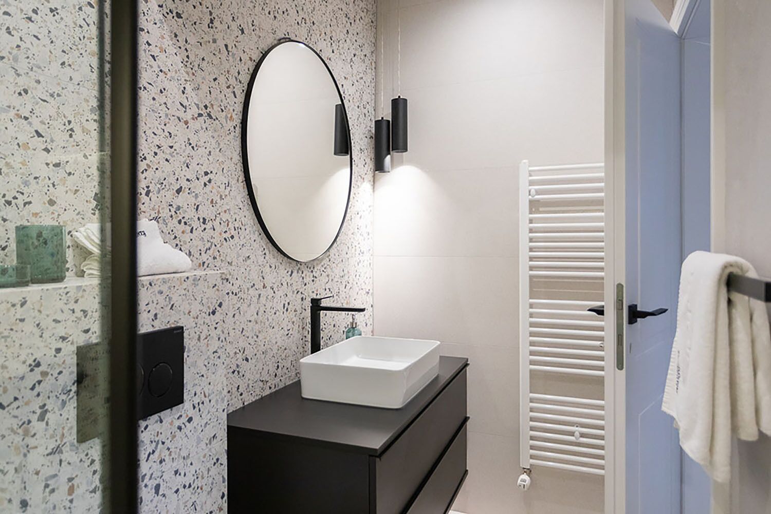 Une salle de bain moderne avec un lavabo sur pied, un miroir rond et un porte-serviettes.