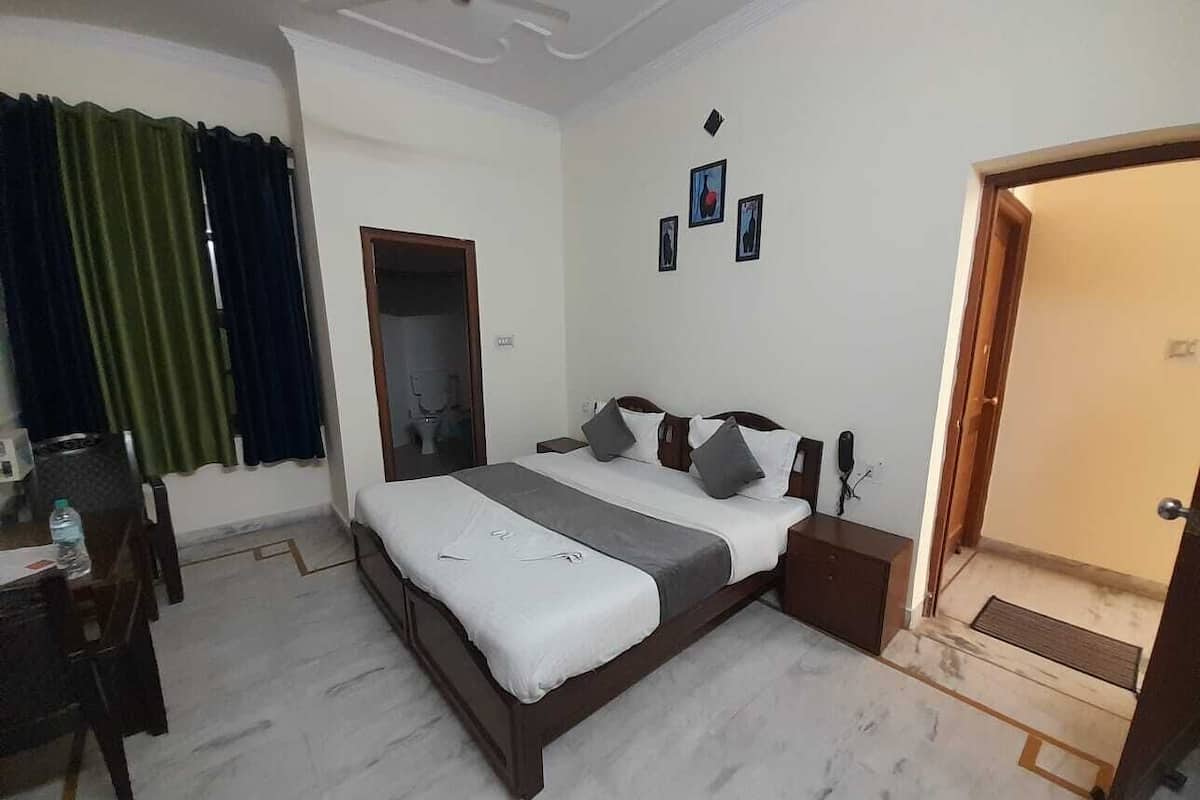 A hotel room with a bed, bedside table, and a small desk with a chair.