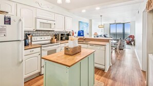 A modern kitchen with white cabinetry, a wooden countertop, and a view to the living area. - 10% off 3-7 nights thru Oct. A BEAUTY! Oceanfront 3 bedroom. Sleeps 6. Outdoor pool (North Myrtle Beach)