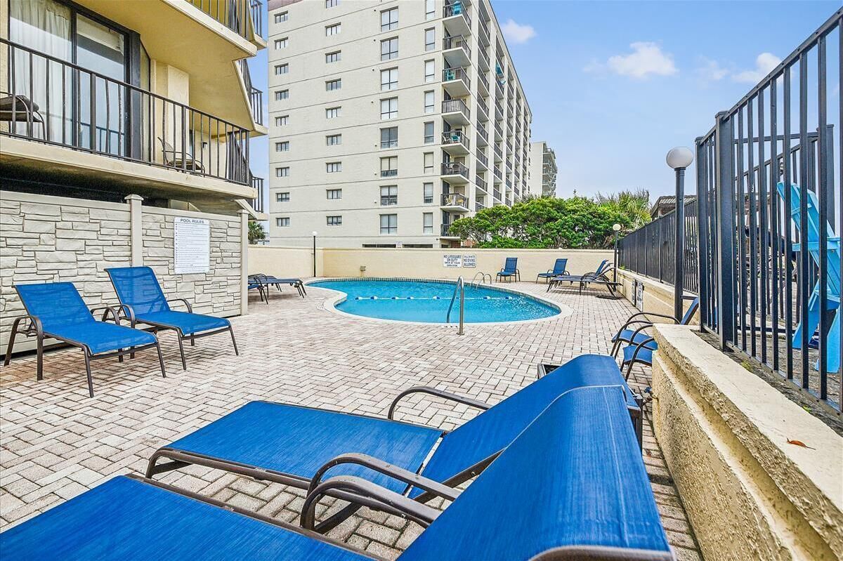 A rooftop pool area with blue lounge chairs and a pool.