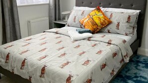 A neatly made bed with a patterned bedspread, a grey upholstered headboard, and a blue rug. - Apartment - Sleeps 4 - Parking - Wifi (Dagenham)