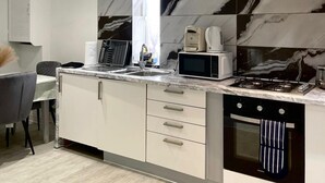 A modern kitchen with a gas stove, microwave, and kettle. There are three drawers and a sink with a faucet. - Apartment - Sleeps 4 - Parking - Wifi (Dagenham)