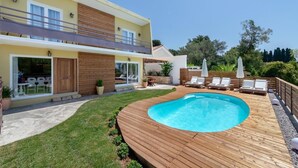Une maison à deux étages avec une terrasse en bois et une piscine.