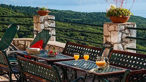 A terrace with outdoor seating, a table with drinks, and potted plants. - Villa Fantasia Kefalonia (Kefalonia)
