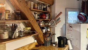 A kitchen with wooden shelves, a black induction cooktop, and a white refrigerator.
