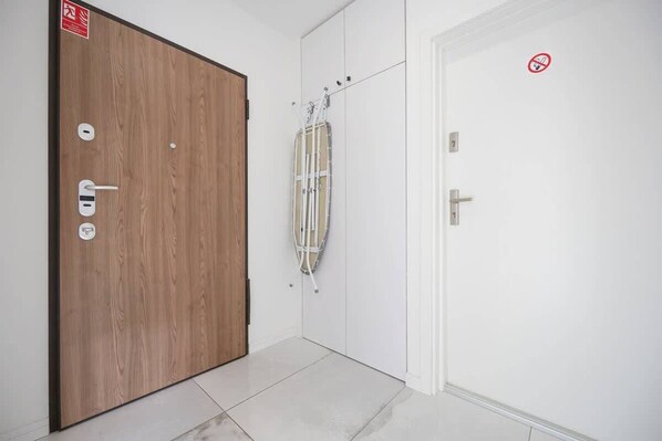 A hallway with a wooden door on the left and a white door on the right, both with electronic locks.