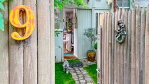 A wooden gate with a number '9' sign, a potted plant, and a small dog in a backyard. - Gorgeous home in Paris with WiFi (Paris)