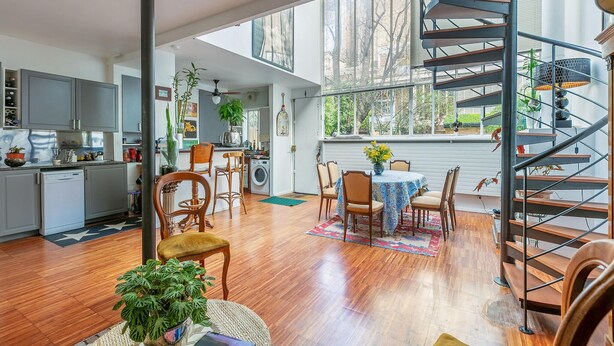 A spacious kitchen with modern appliances, a dining area with a round table and chairs, and a spiral staircase leading to an upper level. - Gorgeous home in Paris with WiFi (Paris)