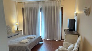 A hotel room with a bed, a chair, a TV, and curtains. - Holiday home with private pool and sea view (Punta de Su Turrione)