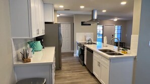 Una cocina moderna con gabinetes blancos, electrodomésticos de acero inoxidable y una isla central con fregadero.