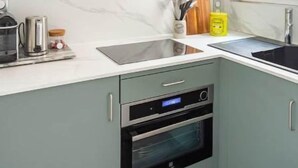 A compact kitchen with a built-in oven, a sink, and a window providing natural light. - Seb's Place Montmartre | Paris Safe and quiet area (Paris)