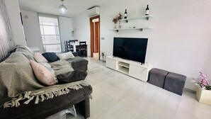 A modern living room with a sofa, TV, and decorative items.