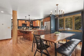 Una cocina moderna con armarios de madera, una isla grande y una zona de comedor con un banco.