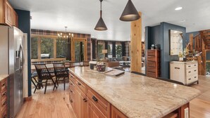 Une cuisine spacieuse avec des meubles en bois, un plan de travail en granit et des luminaires suspendus.