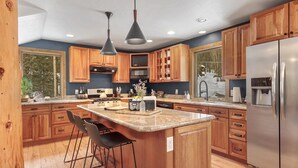 Une cuisine moderne avec des meubles en bois, un réfrigérateur en acier inoxydable et un îlot central doté de tabourets de bar.