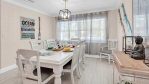 Un espace repas avec une table blanche, des chaises et une statue de Bouddha.
