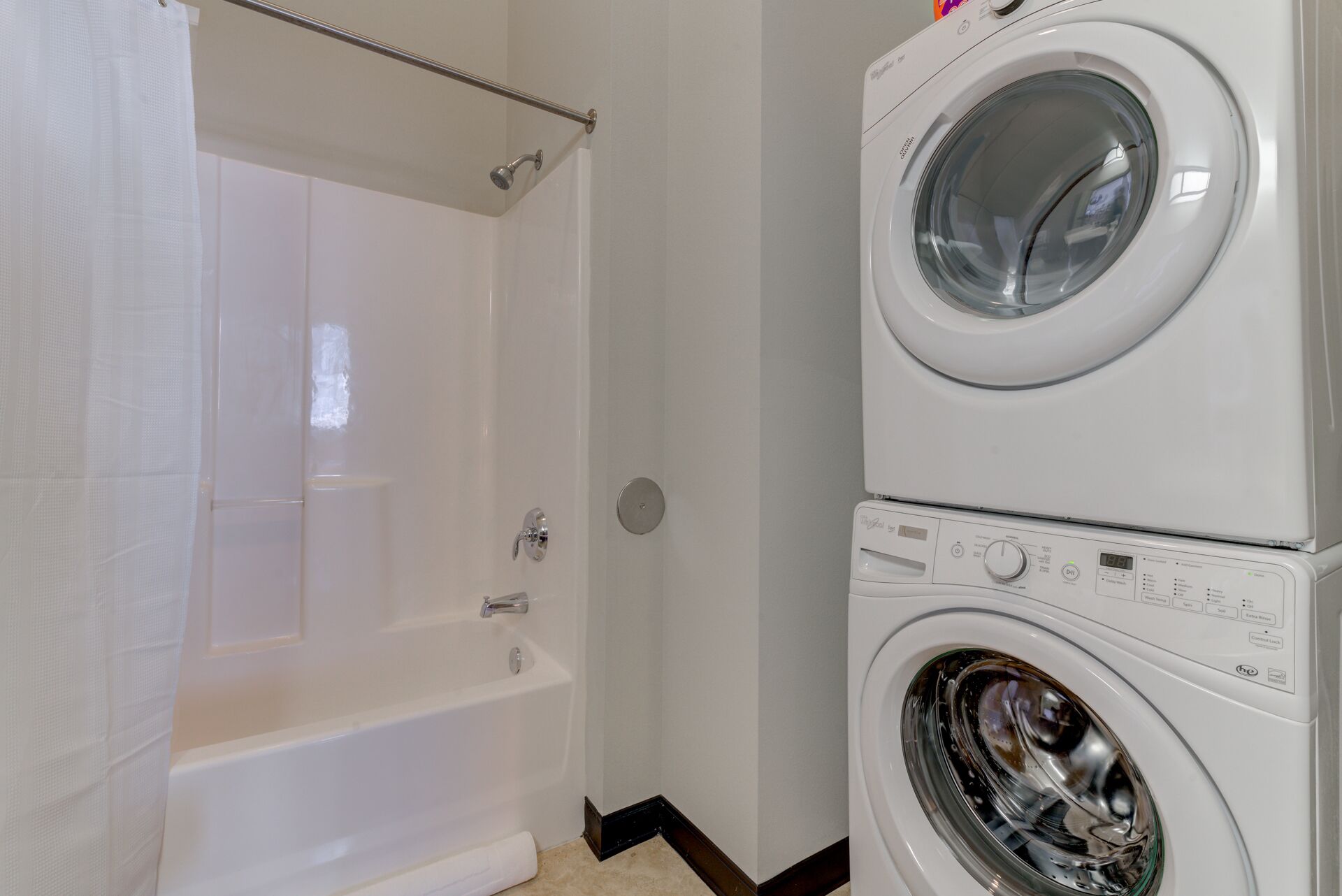 A bathroom with a bathtub, a shower, and a stacked washer and dryer.