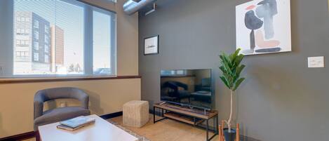 A modern living room with a sofa, a coffee table, a TV, and a potted plant.