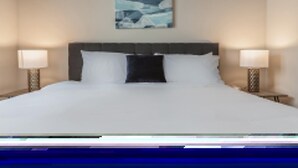 A hotel room with a large bed, two bedside lamps, and a wall-mounted artwork.